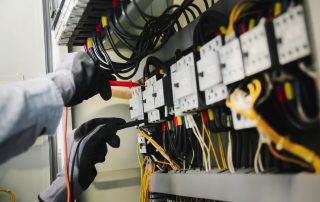 Electrical engineers doing testing and tagging on electrical installations and wiring on protective relays, measuring them with a multimeter.